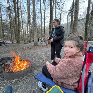 Traveling Trio Family roasting marshmallows by the campfire, camping