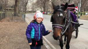 Gluten-Free Traveling Trio Family in New York city exploring Central Park taking picture with a horse